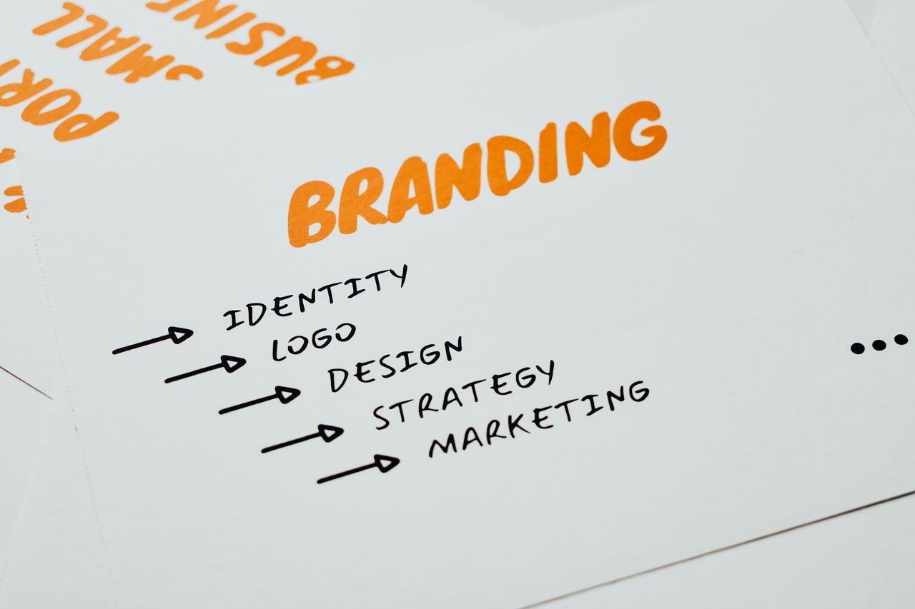 Close-up view of a sheet of paper showing branding, identity, design, strategy, and marketing ideas in orange and black.